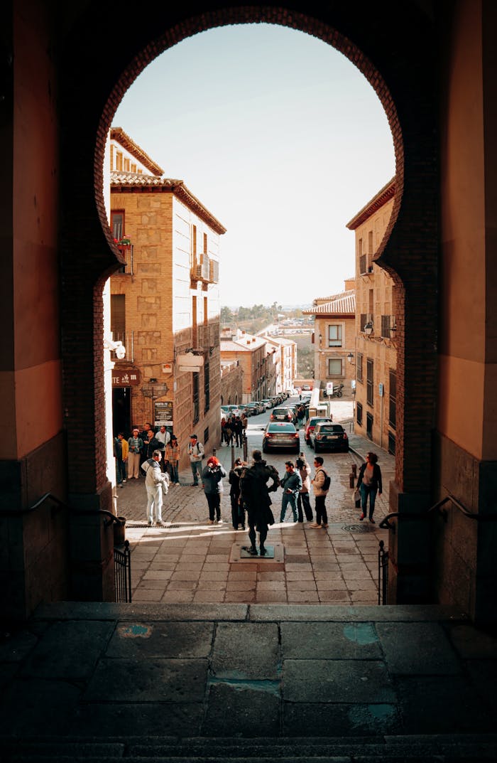 who-we-are View through a medieval archway onto a bustling Spanish street in Toledo, Spain.